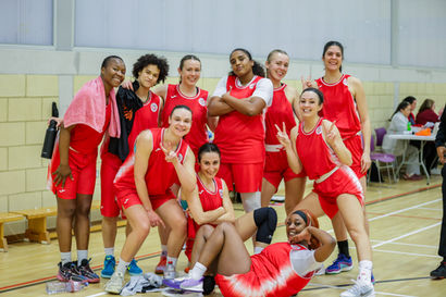 Smiling women's basketball team in red uniforms.