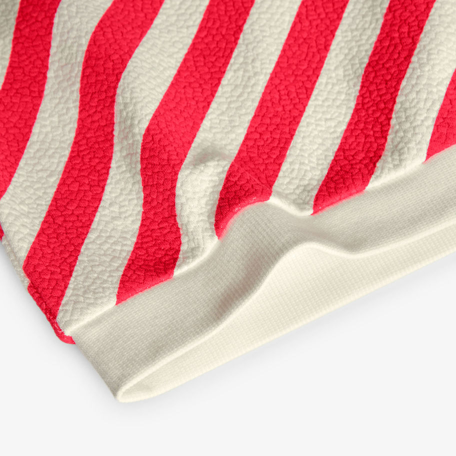 Nahaufnahme gestreifter Stoff in Rot und Beige, Saum eines Kleidungsstücks.