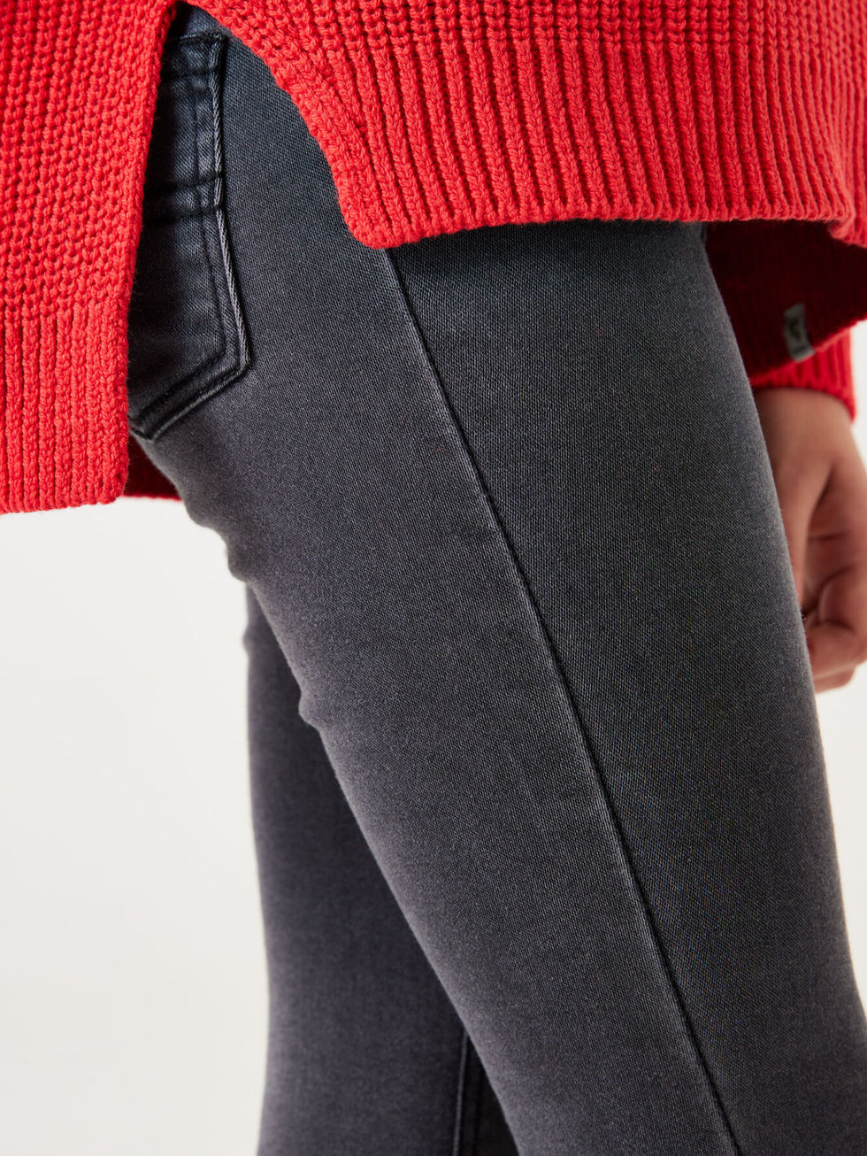 Dunkelgraue Skinny Jeans mit rotem Strickpullover eng anliegend getragen.