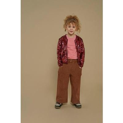 Kind mit lockigem Haar, pinkem Shirt, brauner Hose und gemusterter Jacke.