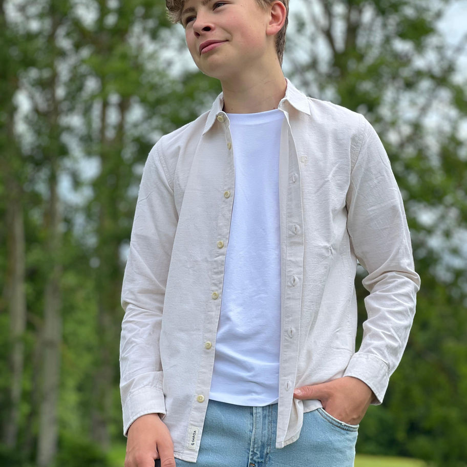 Junger Junge trägt helles Hemd, weißes T-Shirt, Jeans im Freien.