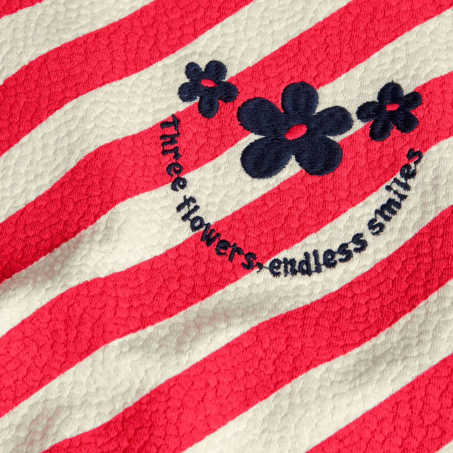 Rot-weiß gestreifter Stoff mit drei Blumen und 'three flowers endless smiles'.