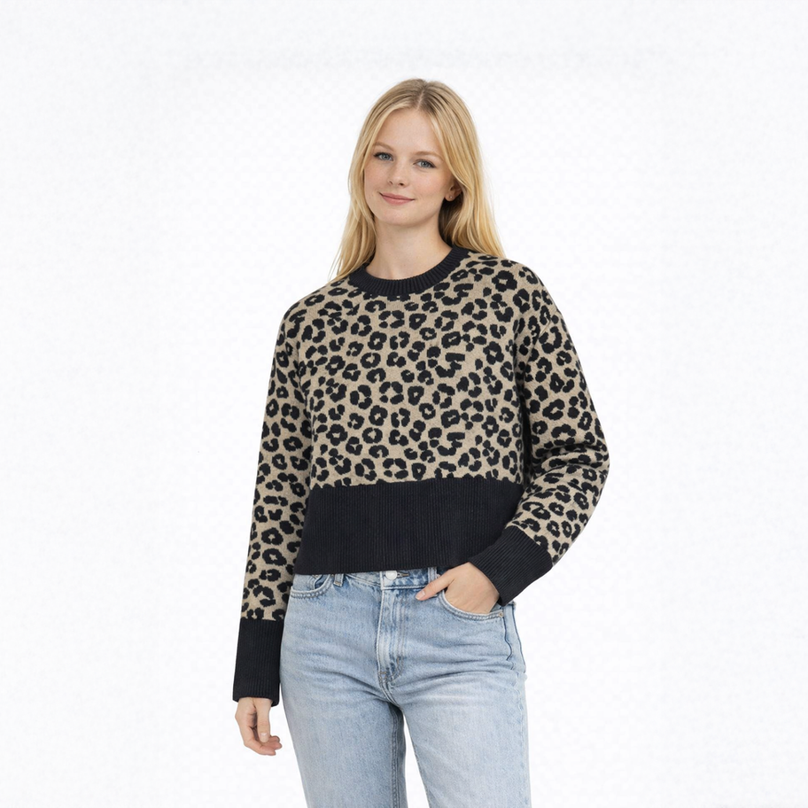 Junge Frau, beiger Leopardenpullover, helle Jeans, lächelt in die Kamera.