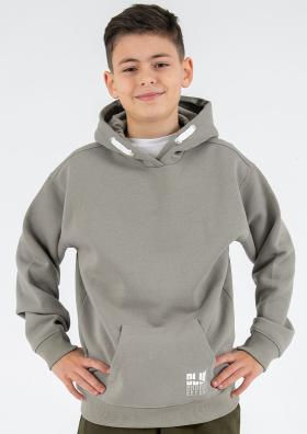 Junge steht lächelnd, trägt grauen Hoodie mit weißen Akzenten.