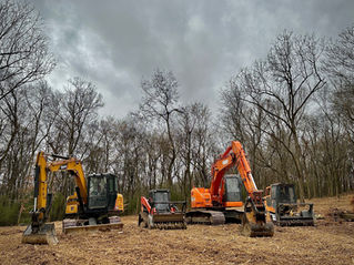 A fleet of American Excavation heavy machinery, including excavators and forestry mulchers, parked on a freshly cleared lot in a Middle Tennessee winter forest.