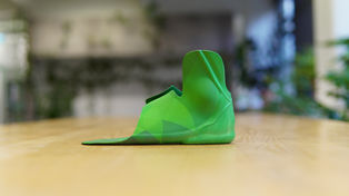 A bright green geometric SMO standing in side profile on a wooden table.