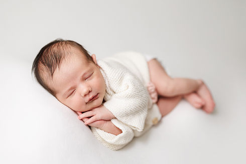 newborn baby girl in side laying pose on white background for professional newborn session portrait