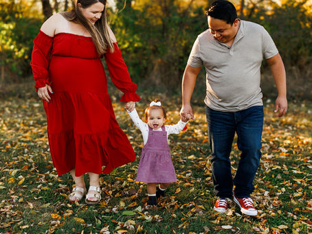 family of 3 walking holding hands with daughter for maternity session portrait