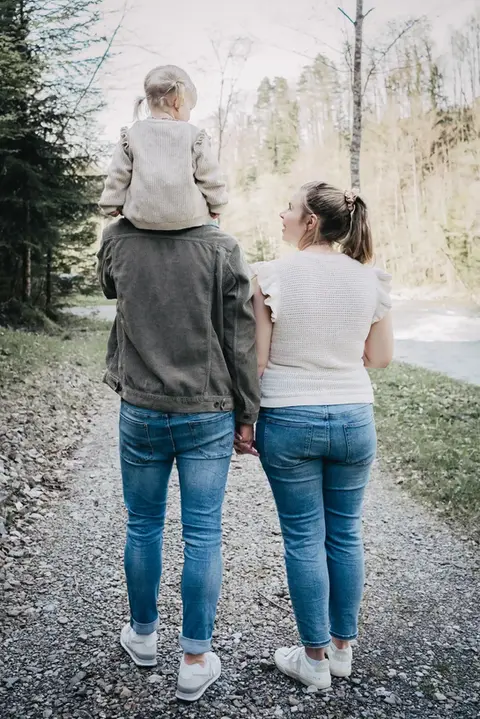 Schwangere Mutter mit Kleinkind und Partner bei einem Outdoorshooting im Park