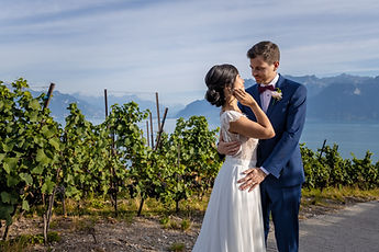 The newlyweds embracing on the vineyard road, facing Lake Geneva