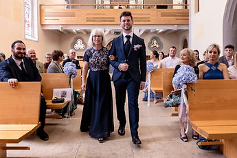 The groom walks up the aisle, watched by the guests