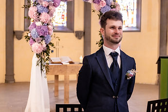 Patrick, smiling, beside the flower arch