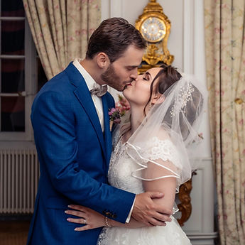 Newlyweds kissing in a drawing room, in front of a gilded clock