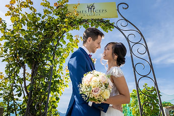 The newlyweds under the arch, the bouquet of roses in the foreground