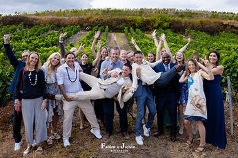 Group photo in the vineyard, the grooms lifted by their guests