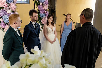 The couple facing the pastor, with their loved ones around them