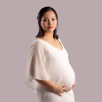 Mother-to-be in white, in profile, hands on her bump, in the studio