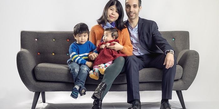 Family of four sitting on a sofa in the studio