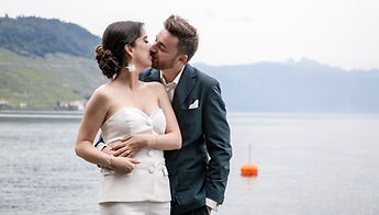 The newlyweds kissing, the slopes of Lavaux behind them