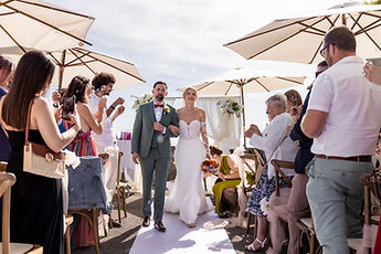 The couple cross the aisle beneath the parasols