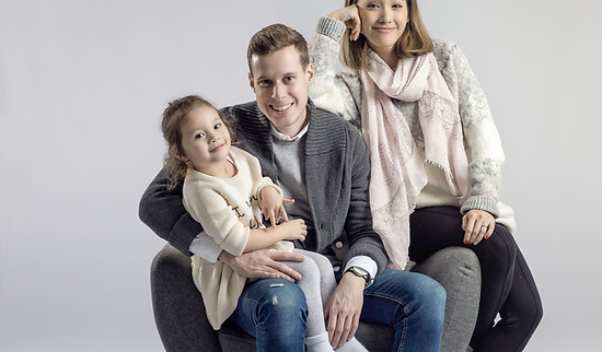 Une petite fille entre ses parents, assis dans un fauteuil au studio