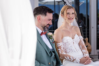 Knowing smiles between the couple, framed by the drapes