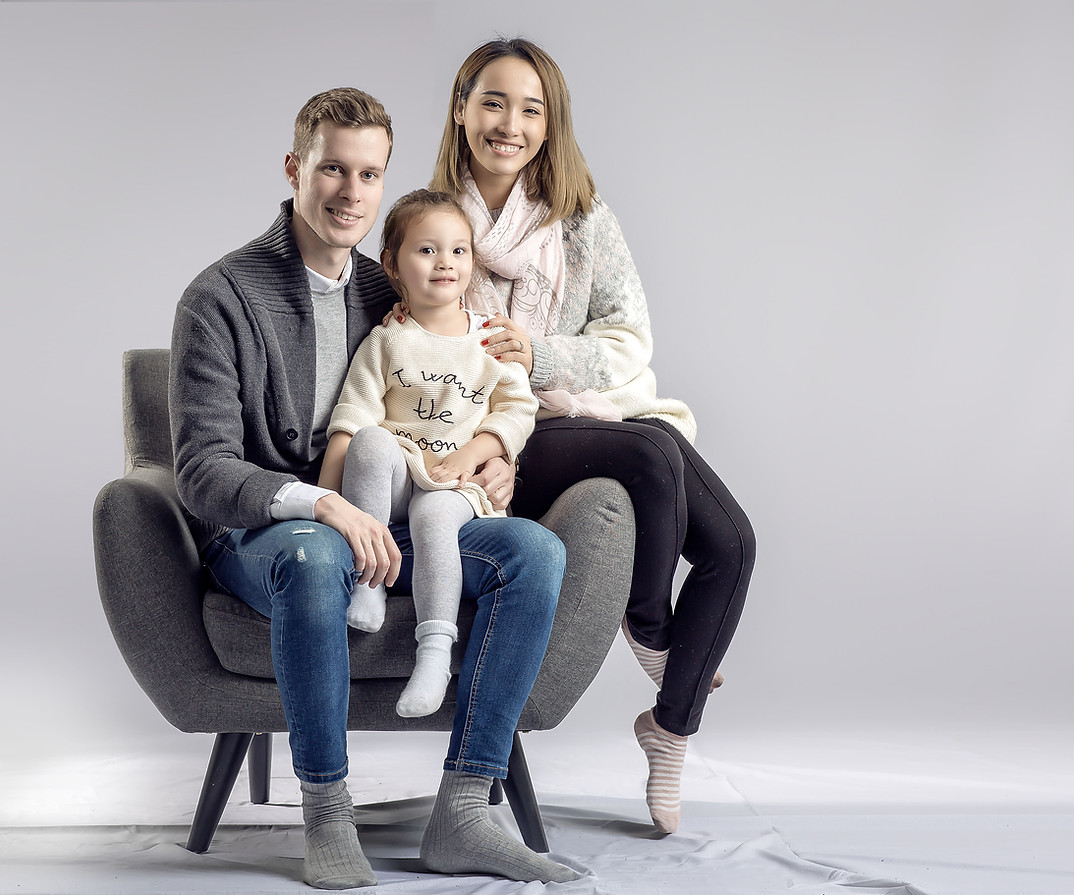 Parents et leur petite fille serrés dans un fauteuil, au studio