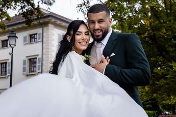The couple smile behind the outspread cape