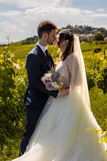 The couple embracing between the rows of vines