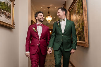 Loïc and Boris walk hand in hand down a hotel corridor