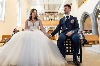 The couple seated hand in hand during the ceremony