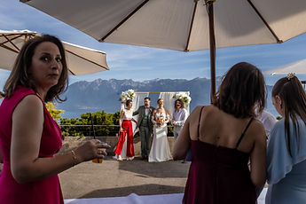 Guests chatting beneath a parasol, the couple in the distance