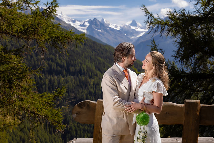 Charlotte and Derek embracing in Chandolin, facing the snow-capped peaks of the Val d'Anniviers