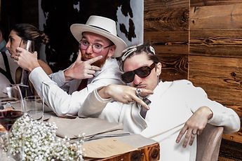 Two guests striking a pose, hat and dark glasses