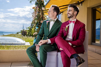 The grooms laugh, seated side by side