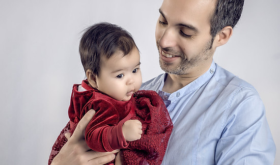 Un papa souriant tient son bébé dans les bras