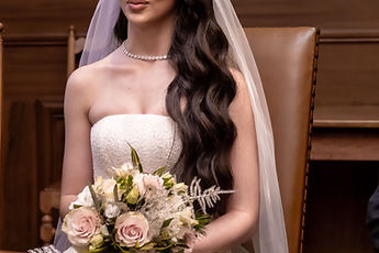 Leonora seated, her bouquet on her lap