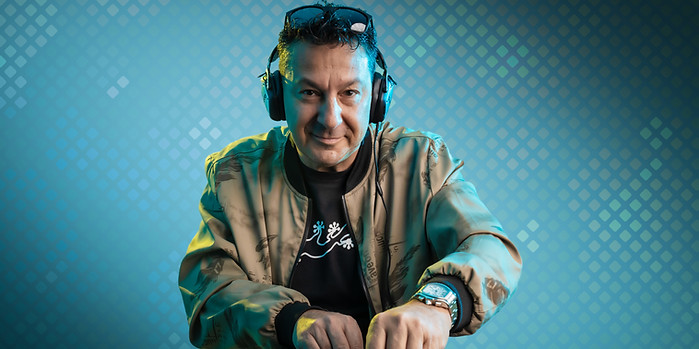 Professional portrait of a DJ behind his decks, headphones on