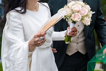 Detail: the sleeve of the dress, the fan and the bouquet