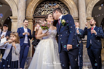 The newlyweds kissing under the bubbles, surrounded by their guests