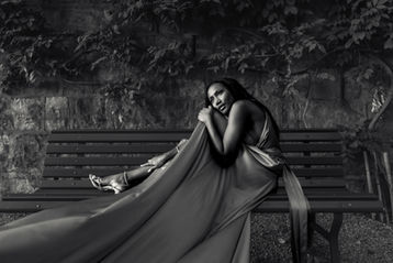 Woman in a long dress sitting on a park bench, black and white