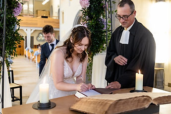 Lucie signs the register beside the pastor