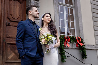 The newlyweds in front of a window trimmed with red bows