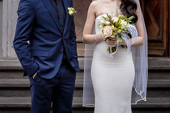 Detail: the blue suit and the white dress, bouquet in hand