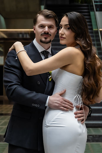 The couple embracing in front of the lobby staircase