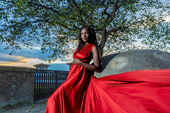 Maternity photo session in a red dress in front of a tree