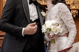 Detail: the bride's bouquet against the groom's tuxedo