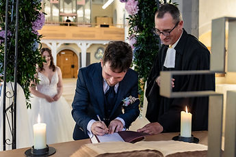 Patrick signs the register as the pastor looks on