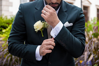 Detail: Marouan adjusting his cuff, a white rose in his buttonhole