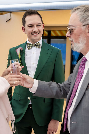 A guest clinks glasses with one of the grooms